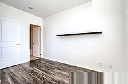 Empty bedroom with a bare wall and hardwood floor before virtual staging