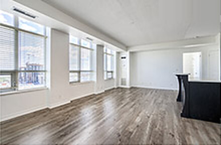 Empty condo living room with hardwood floors and floor-to-ceiling windows before virtual staging
